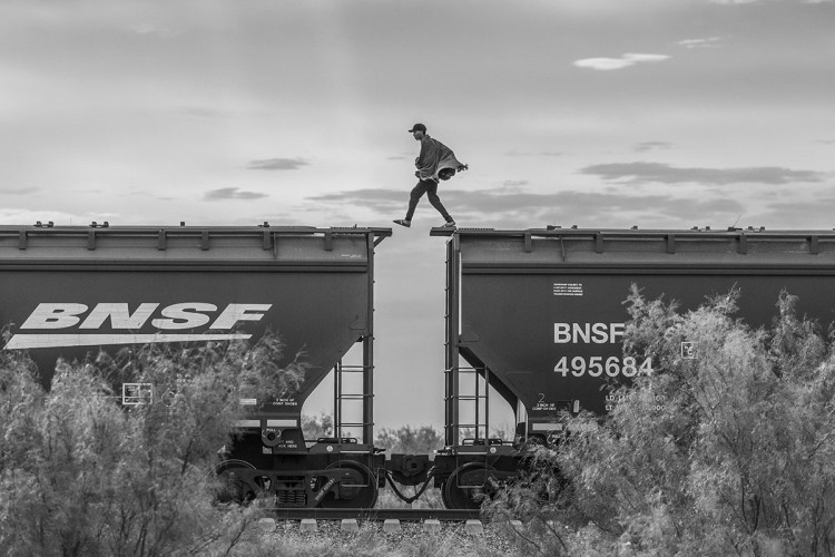 Fotografija pokazuje migranta kako hoda po vozu. MIgranti u nedostatku novca, često pribjegavaju prevozu teretnim vozovima kako bi stigli do granice sa SAD-om. Tokom godine, stotine migranata na ovaj način izgubi život. 